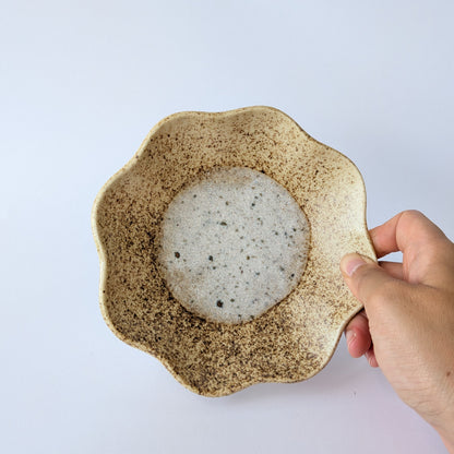 Hand holding a ceramic bowl with a textured exterior on a light gray background